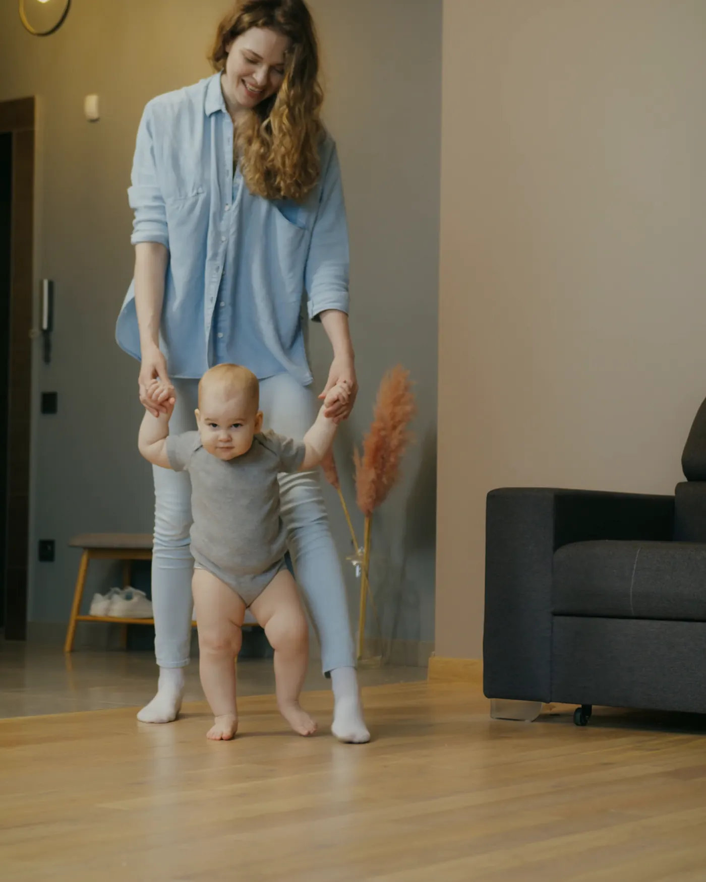 Mãe ajudando o bebê a caminhar sobre piso laminado amadeirado